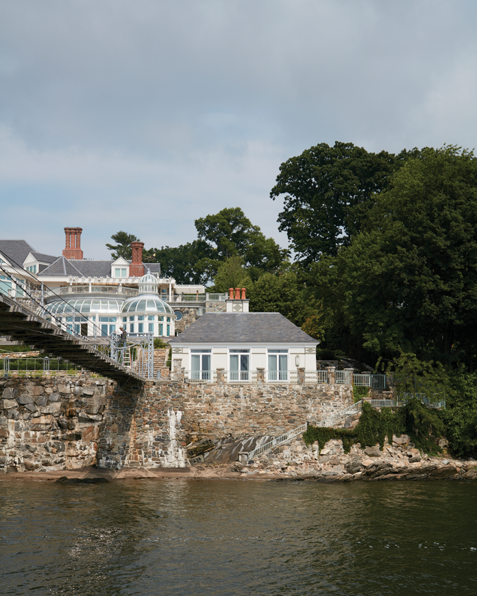 A view from the water shows the main house and boathouse, which is built into the surrounding rock wall.