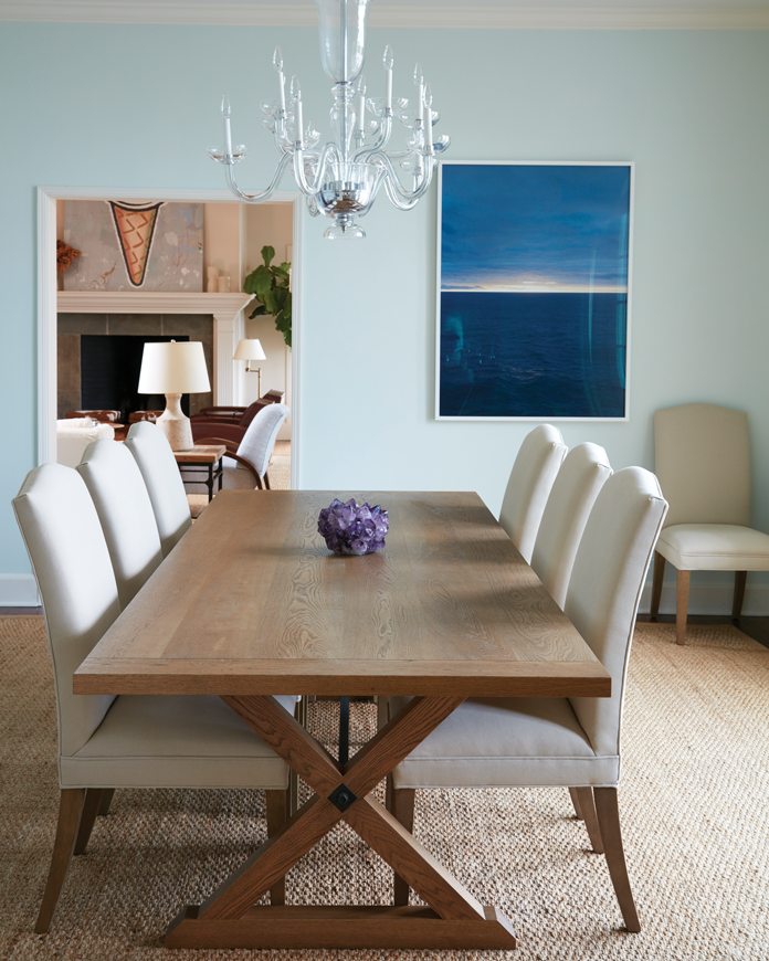 The dining room is casual yet refined with sisal carpeting, a vintage Murano chandelier and a custom oak plank table by KWH Furniture in Brooklyn. The sunset artwork is by Catherine Opie.