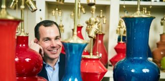 Christopher Spitzmiller surrounded by red and blue lamps he has made by hand.