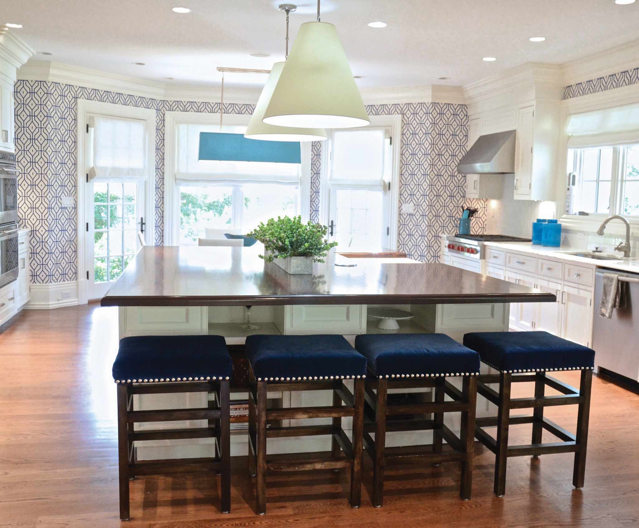 A kitchen designed by D2 Interiors with blue and white wallpaper and blue stools as a focal point.