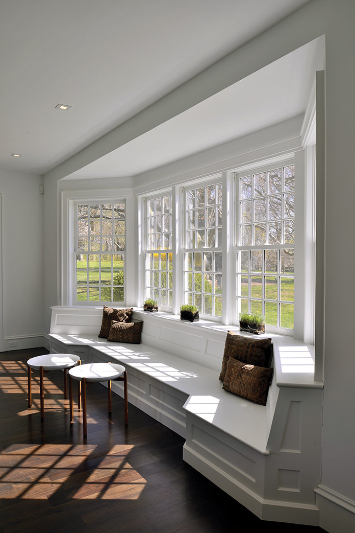 The existing window seat was reimagined in this  renovation, accented with lens tables from Holly Hunt.