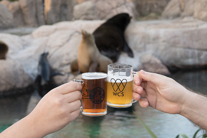 Two hands holding beer glasses at the zoo