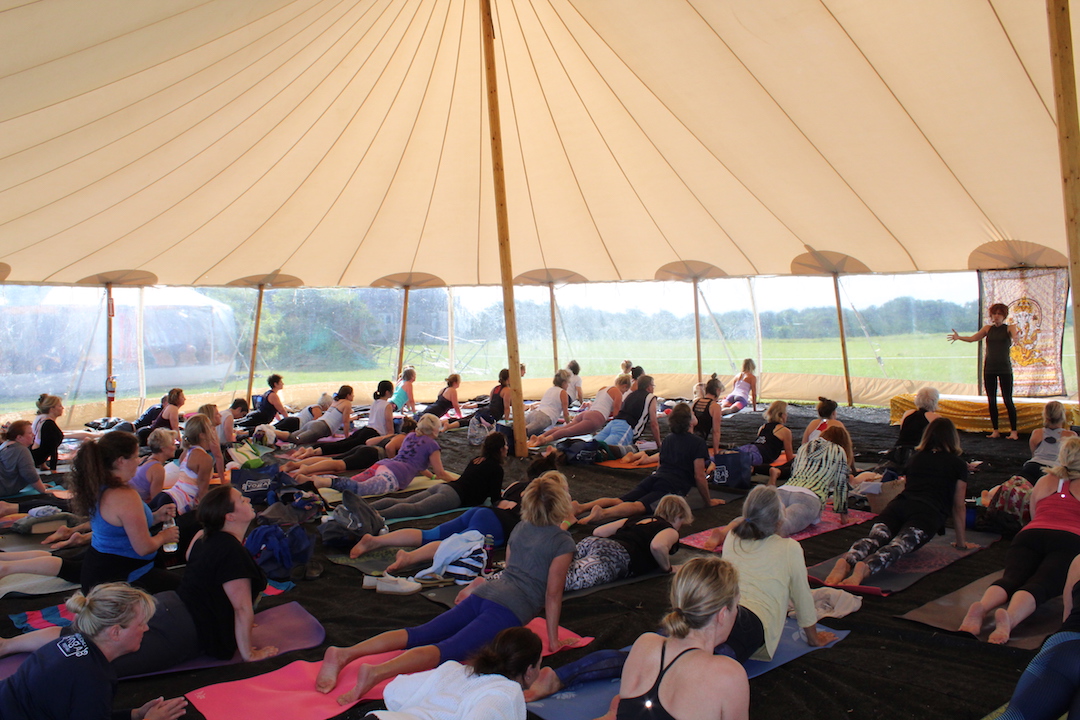 A group doing yoga under a tent