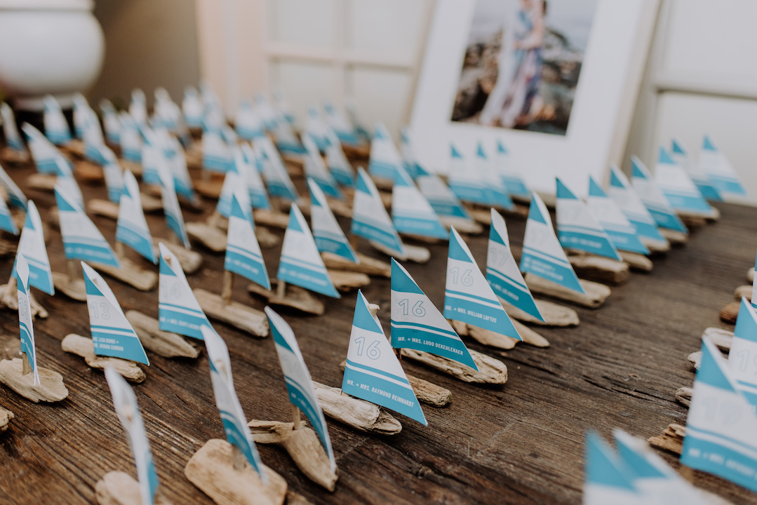 Mini sailboats handmade out of driftwood served as place cards.