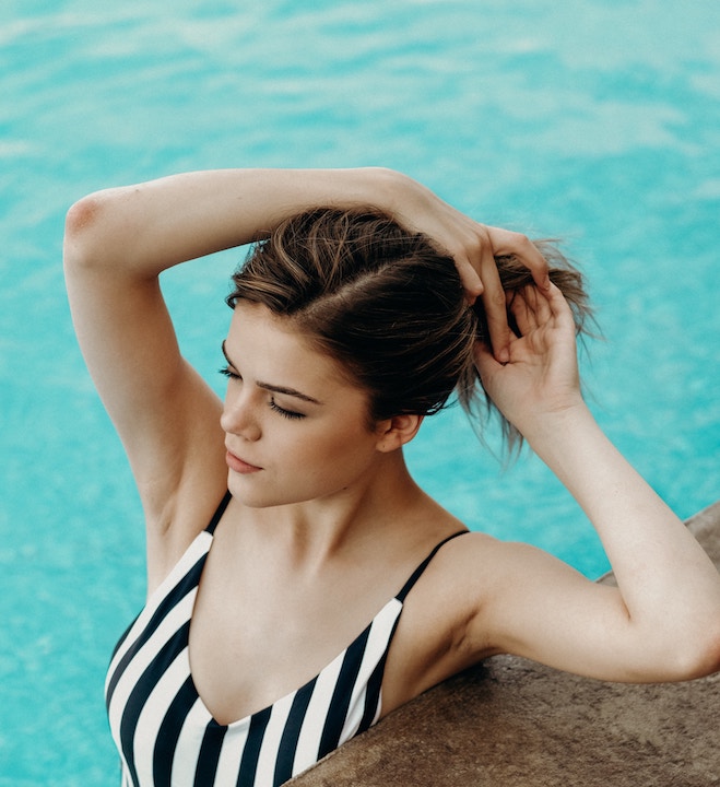 Woman in pool holding up her hair